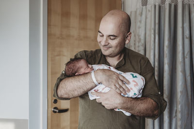 Happy father holding newborn boy wrapped in blankets in hospital