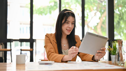 Portrait of young woman using digital tablet at office