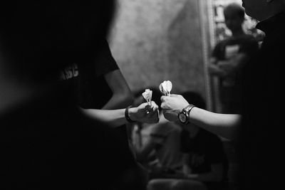 Cropped hands of people holding objects in darkroom