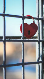 Close-up of padlocks on fence against sky