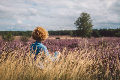 Rear view of woman standing on field against sky