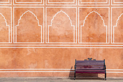 Empty bench against wall in old building