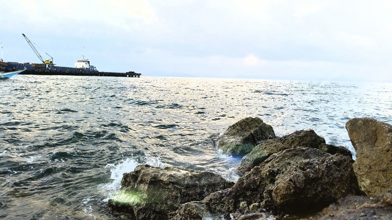 sea, water, sky, nautical vessel, horizon over water, transportation, scenics, tranquil scene, mode of transport, nature, rock - object, tranquility, beauty in nature, boat, built structure, cloud - sky, day, rippled, outdoors, waterfront