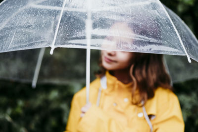 Portrait of woman looking through wet window during rainy season