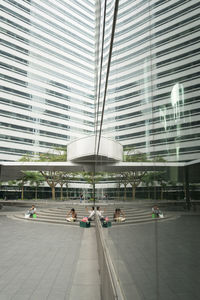 People walking on modern glass building in city