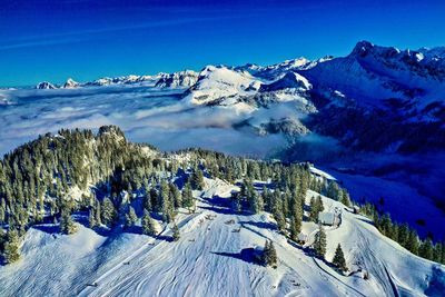 Scenic view of snowcapped mountains against blue sky