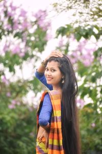 Portrait of smiling young woman standing against plants