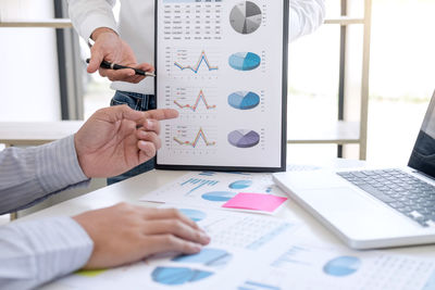 Midsection of businessmen working over graphs in office