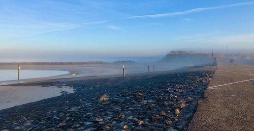 Scenic view of misty coastal road against sky during winter