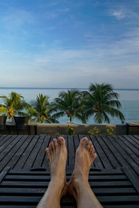 Low section of woman relaxing on beach against sky