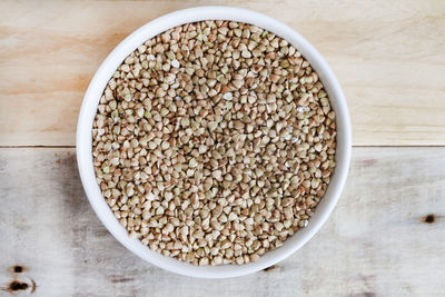 Bowl full of whole buckwheat on rustic surface with copy space