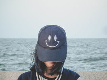 Woman wearing cap against sea at beach