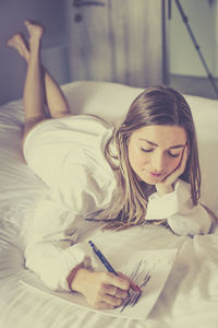 Portrait of young woman sitting on bed at home