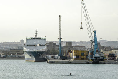 Cranes at harbor against sky