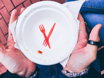 Directly above view of man holding empty disposable plate in hand