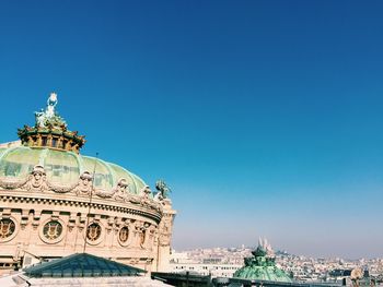 Statue in city against clear blue sky