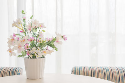 Flower vase against white wall at home