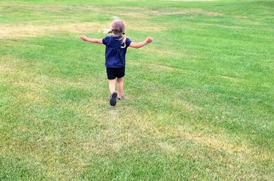 Rear view of girl running on field