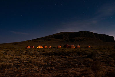 Camping on top of mountain on a starry night  with glowing tent