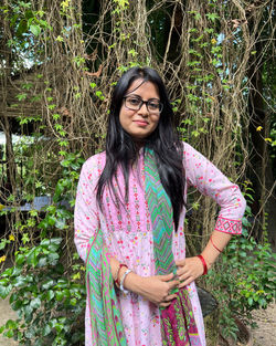 Portrait of young woman standing against plants
