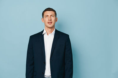 Portrait of businessman standing against gray background