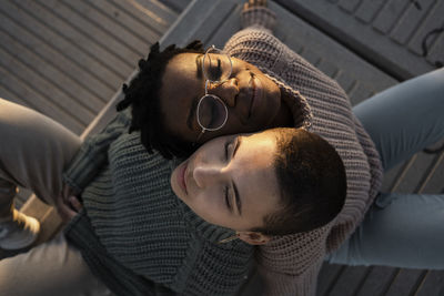 Young women leaning on each other shoulder while sitting on bench