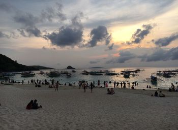 People at beach against sky during sunset