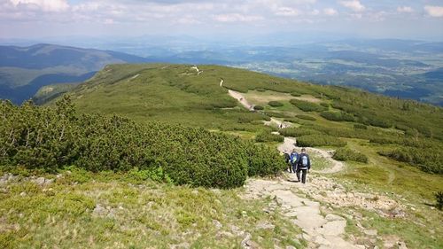 Rear view of people walking on mountain against sky