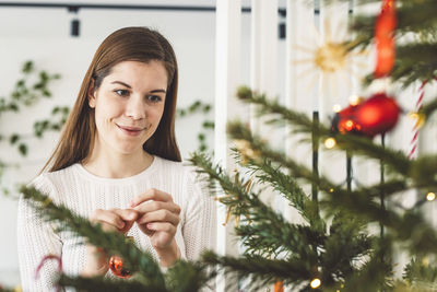 Portrait of young woman against christmas tree