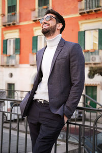 Mid adult man standing by railing in city