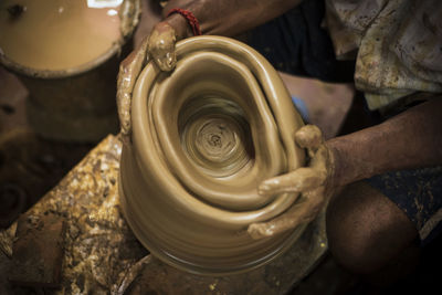 Midsection of potter making pot at workshop