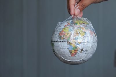 Cropped hand holding globe in plastic bag