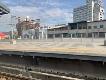 Railroad tracks by buildings in city against sky