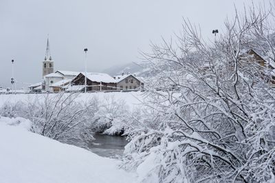 Houses on snow covered landscape against sky