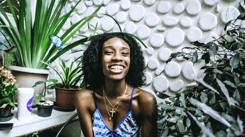 Portrait of smiling young woman standing against plants