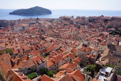 High angle view of residential district by sea against clear sky