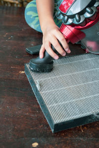 A young boy is cleaning the air filter sheet with the vacuum.