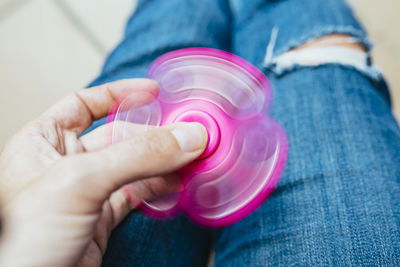 Midsection of person spinning pink fidget spinner