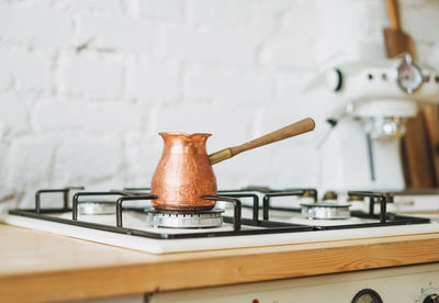 Coffee copper pot on stove at bright kitchen, morning routine