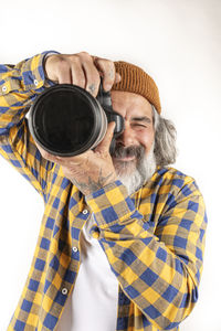 Portrait of man photographing through camera against white background