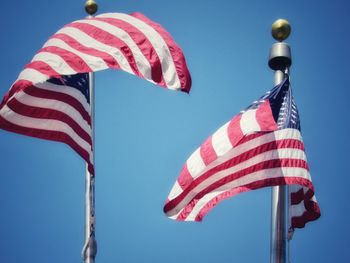 Low angle view of flags against blue sky