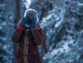 Woman photographing through camera while wearing warm clothing during winter