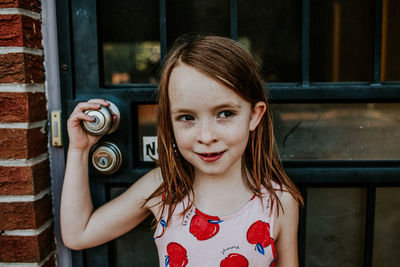 Young girl looking away and holding on to front door