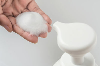 Close-up of hand holding ice cream over white background