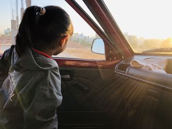 Side view of child looking through car window