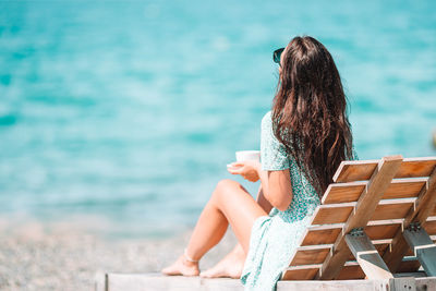 Woman sitting on chair at sea shore