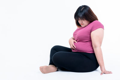 Woman sitting against white background