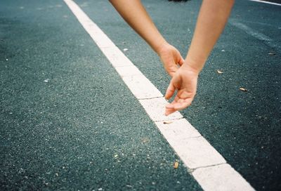 Low section of woman walking on road in city