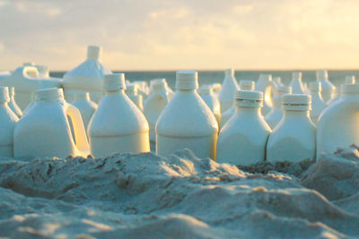 Close-up of bottles on sand at beach during sunset