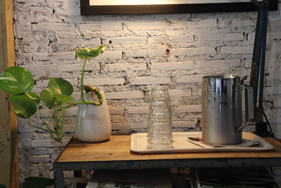 Plants in jar on table by wall at home